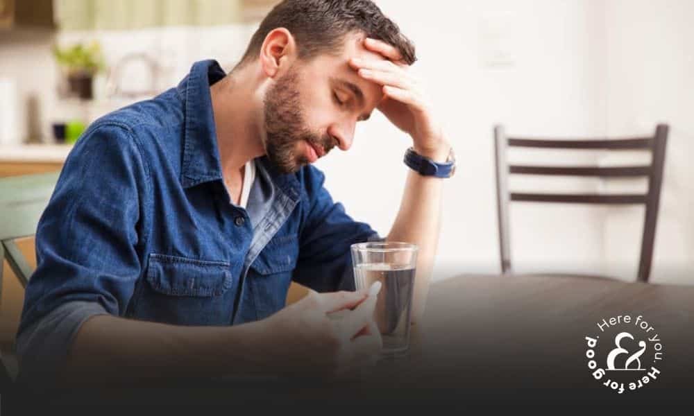 tired man about to take a pill with water