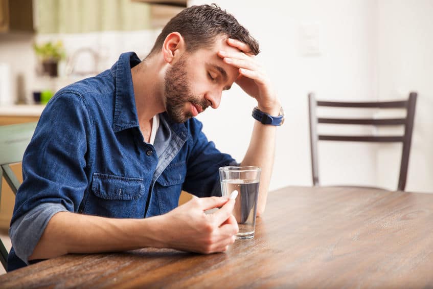 tired man about to take a pill with water