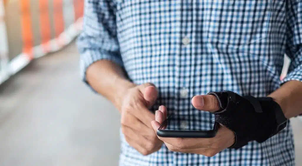 man with injured wrist looking at phone