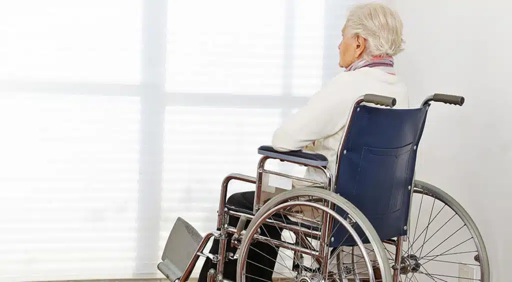 old man in wheelchair looking out window