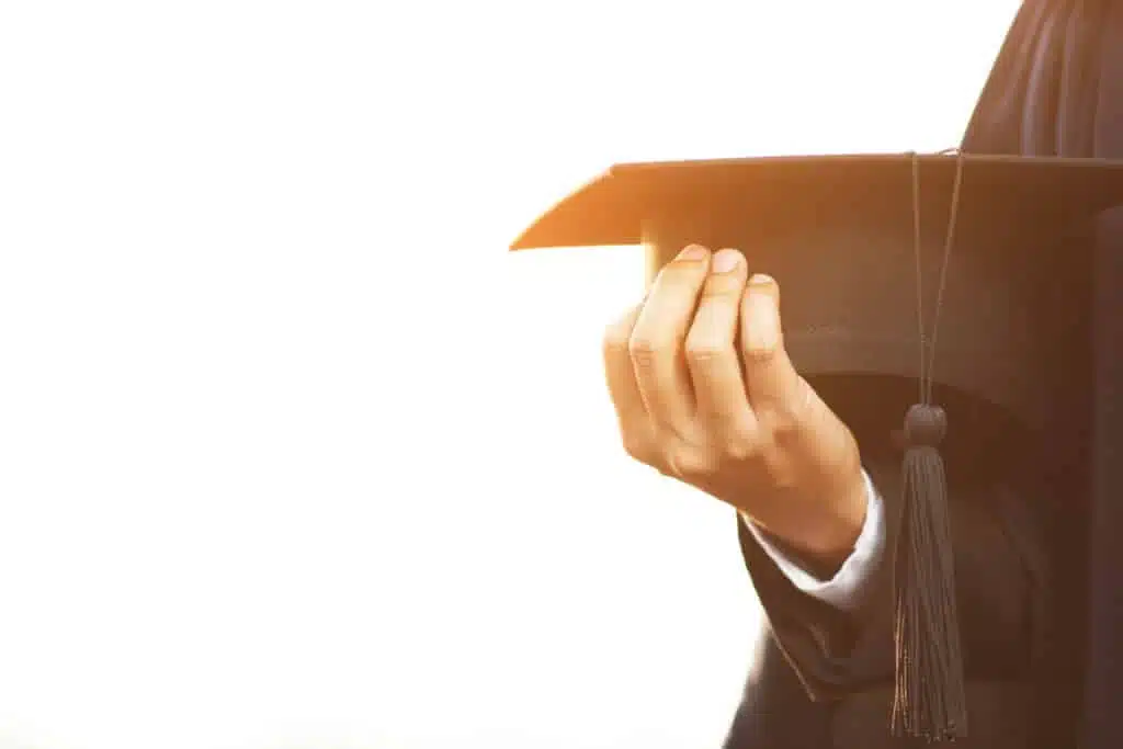 close up people show hand hold show hat in background School building. Shot of graduation cap during Commencement University Degree Concept , Celebration Education Student Success Learning Concept.