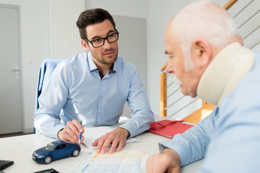 a man talking to an elderly man while filling a form