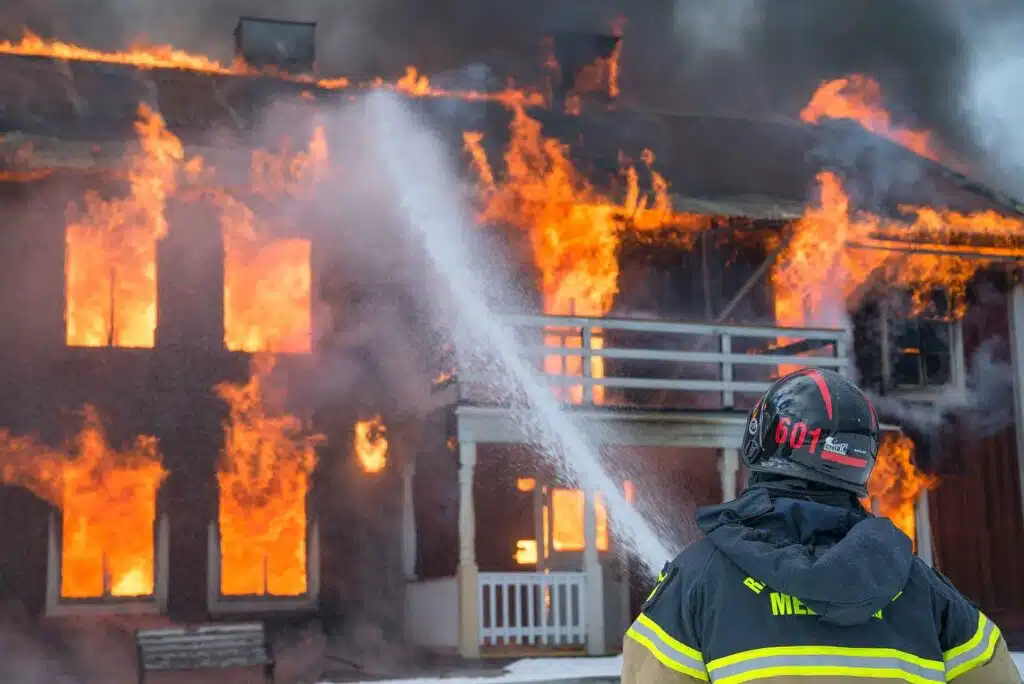 a burning house and fireman shooting water at it