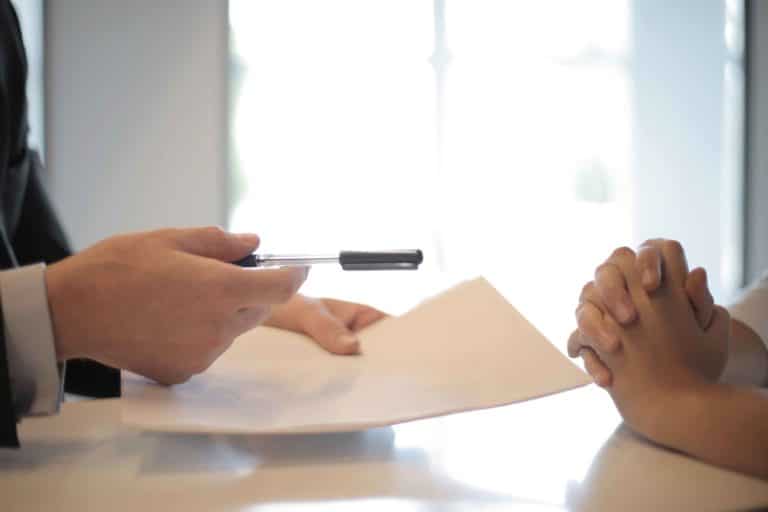 A lawyer handing a pen and document to someone to sign