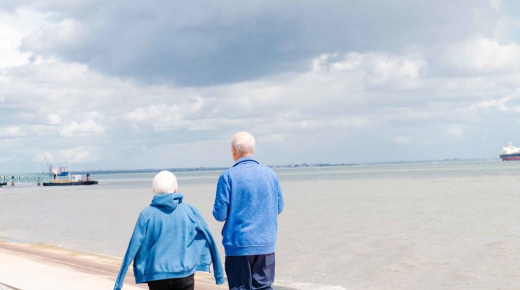 Two elderly people walking by the seaport