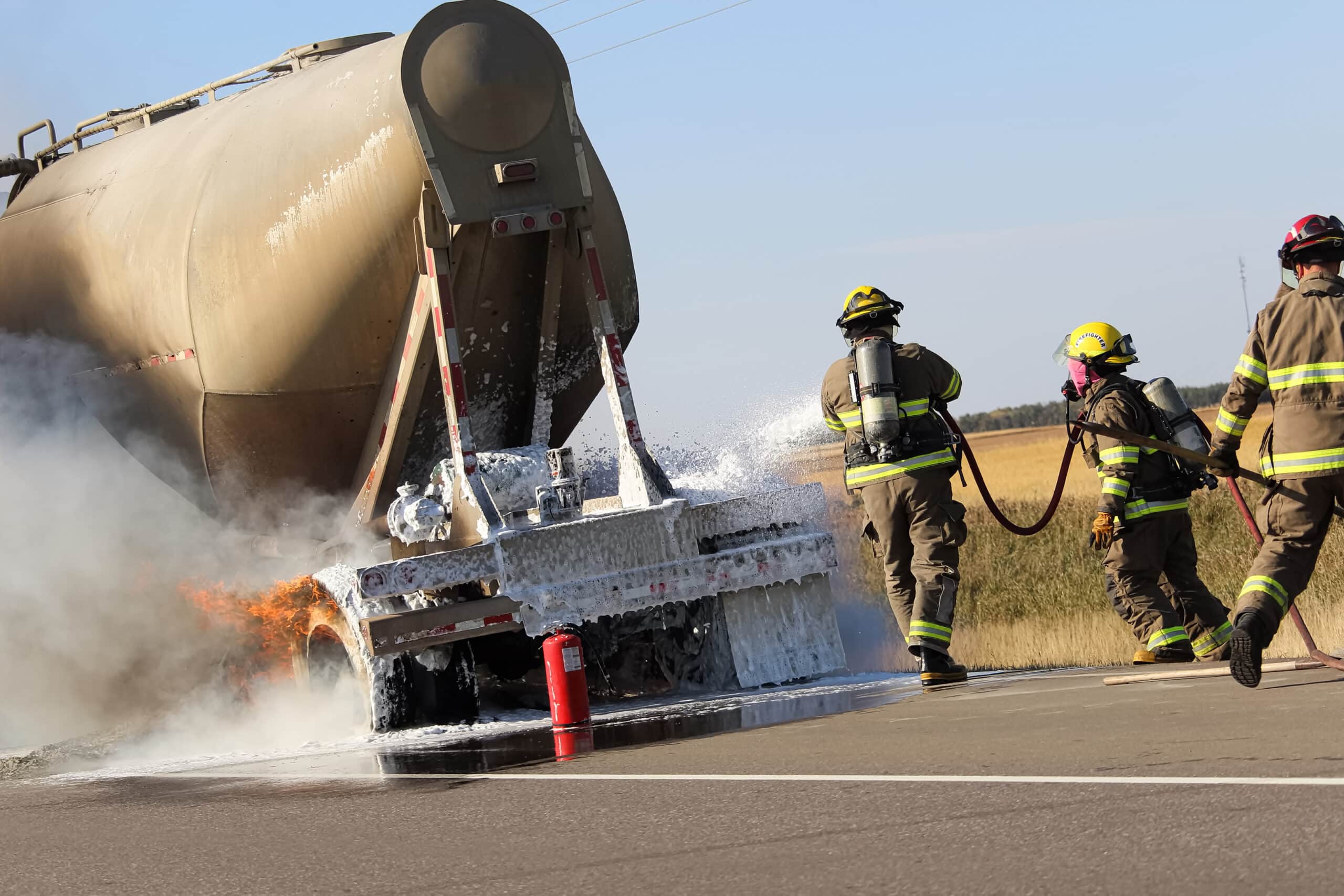 Three fireman rush to put out a brake fire on a semi-truck