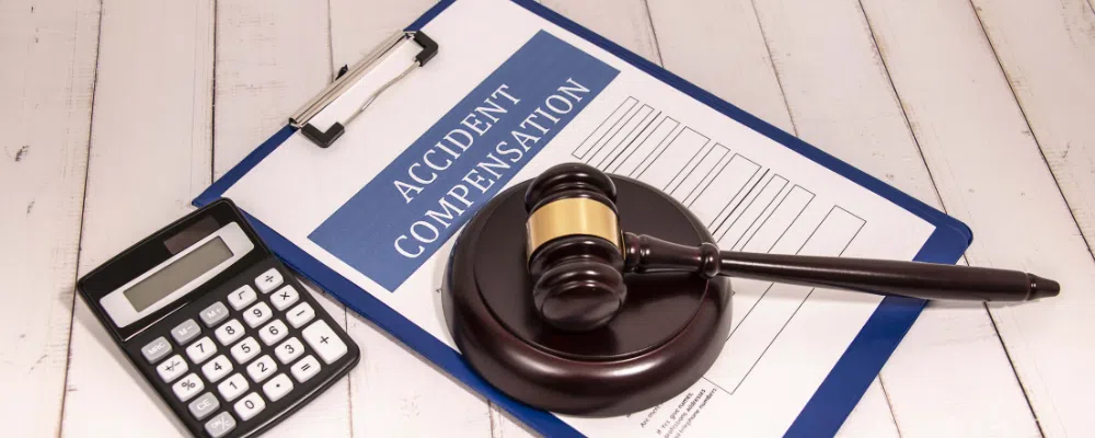 workers comp paper on clipboard with gavel and calculator