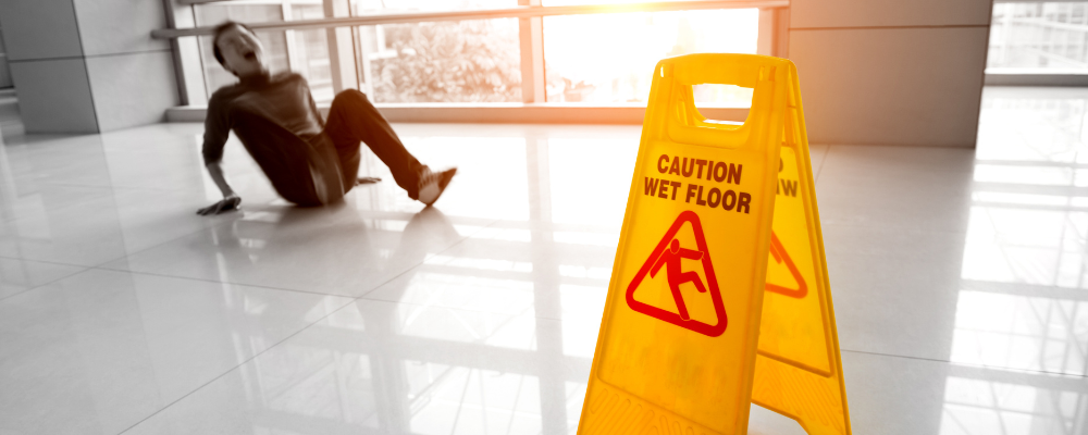man slips on white marble floor next to caution sign