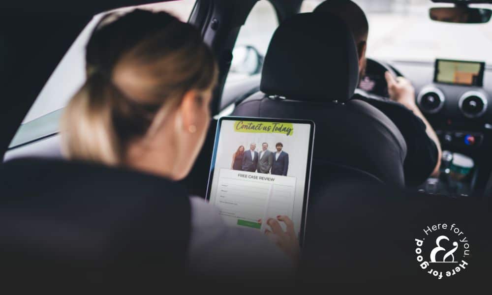 a passenger sitting in the back seat of an Uber viewing an Uber attorney website on a tablet