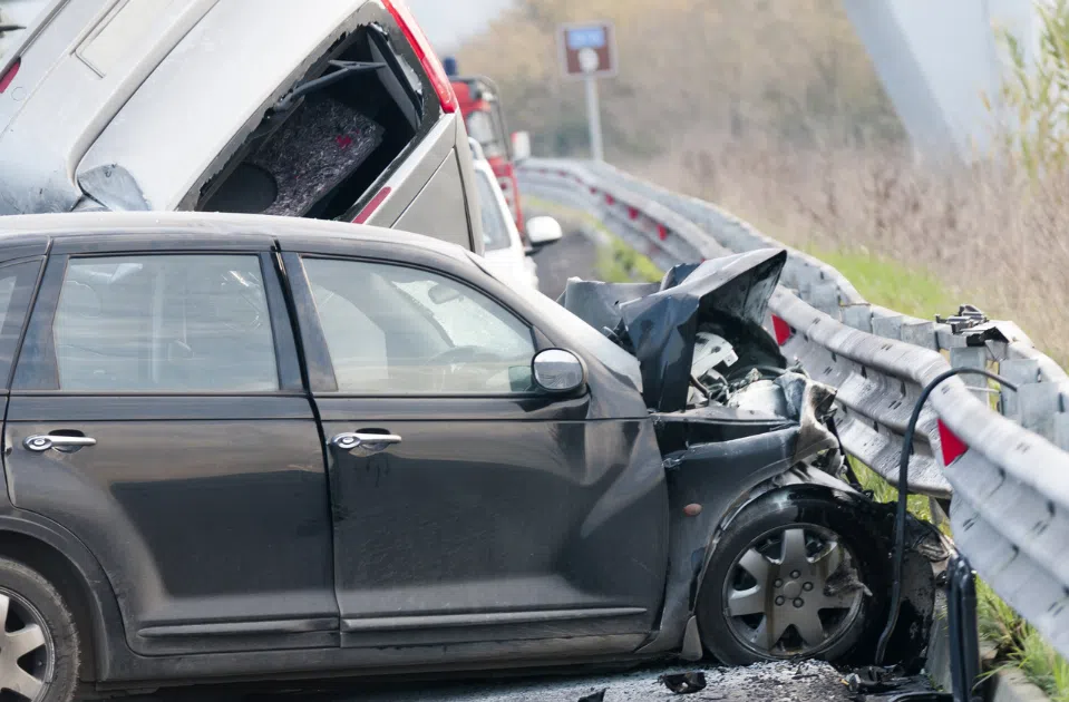 white truck and black car collide into guardrail on a highway