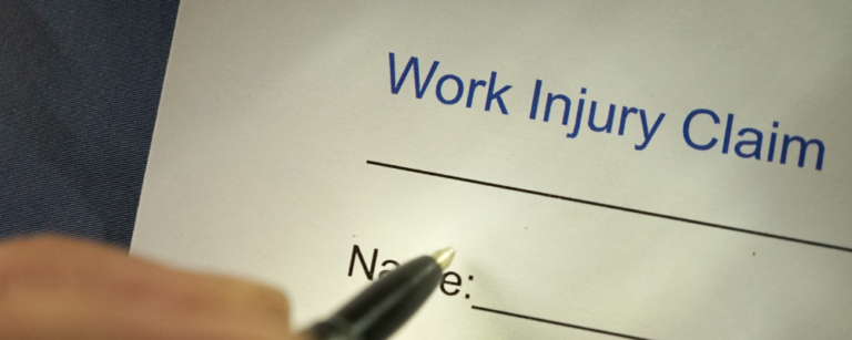 person filling out a work injury claim form with a pen - workers compensation attorneys in Florida and Georgia