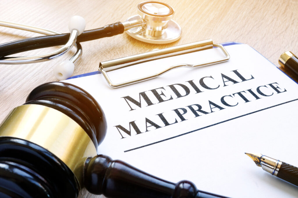 a gavel and stethoscope on a table with a clipboard that reads medical malpractice