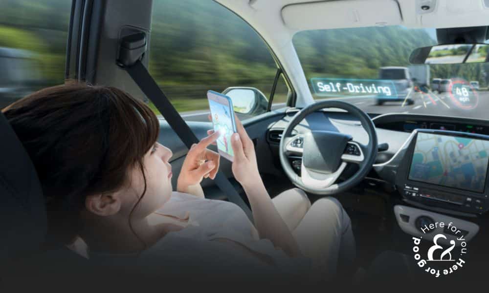a woman using her cell phone will sitting in the driver's seat of a self-driving car
