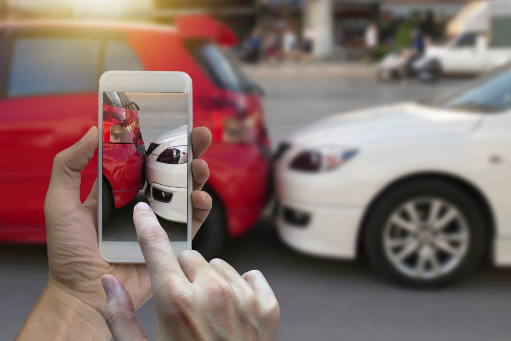 Close up hand holding smartphone and take photo at The scene of a car crash and accident, car accident for car insurance claim.