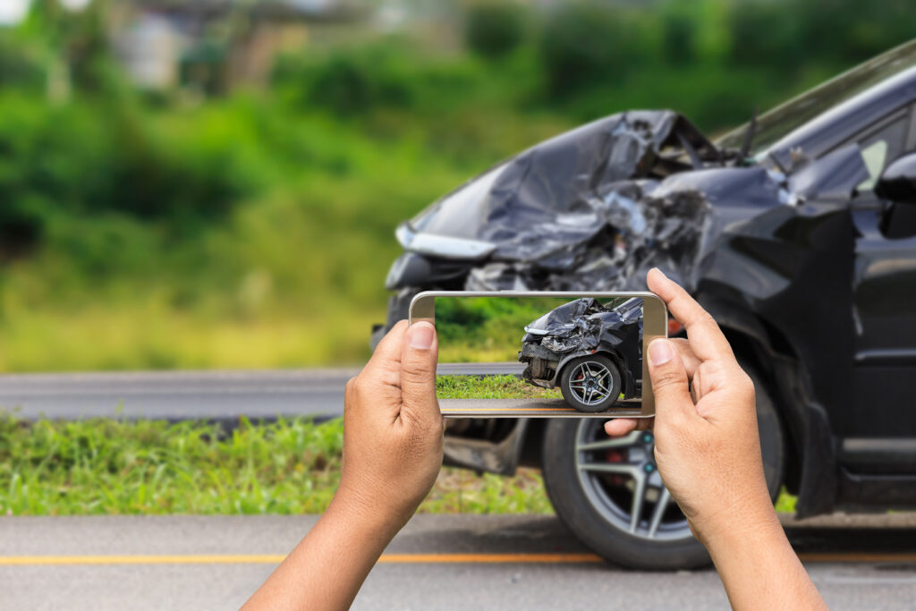 someone taking a photo of damage after a hit and run car accident as evidence for an insurance claim