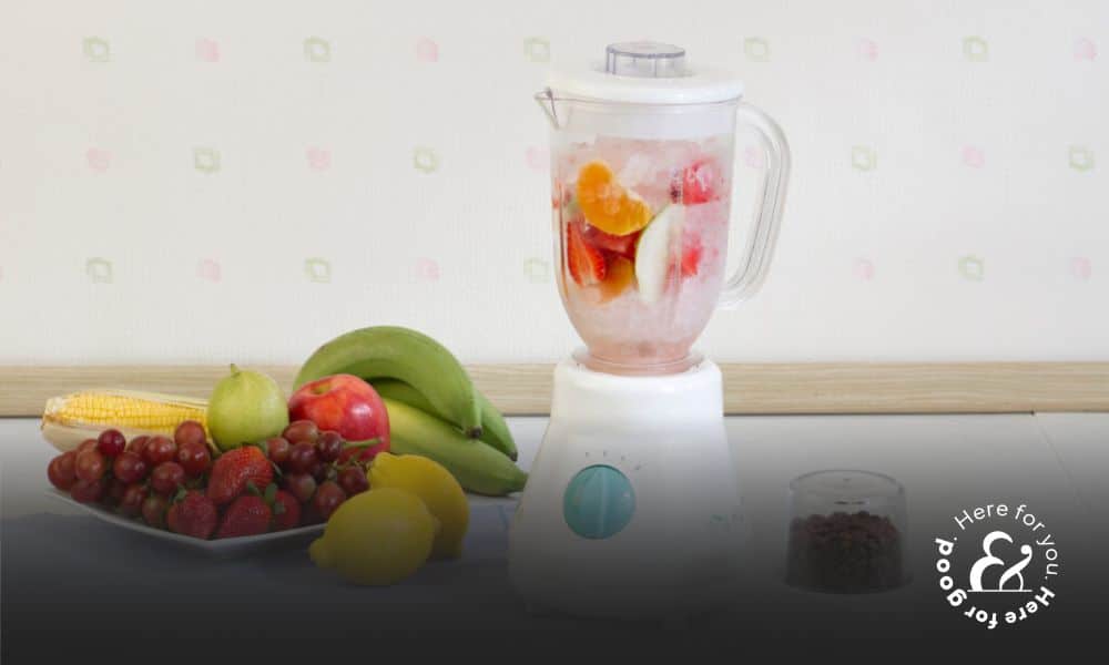 a portable blender next to fruit and a cloth on a table
