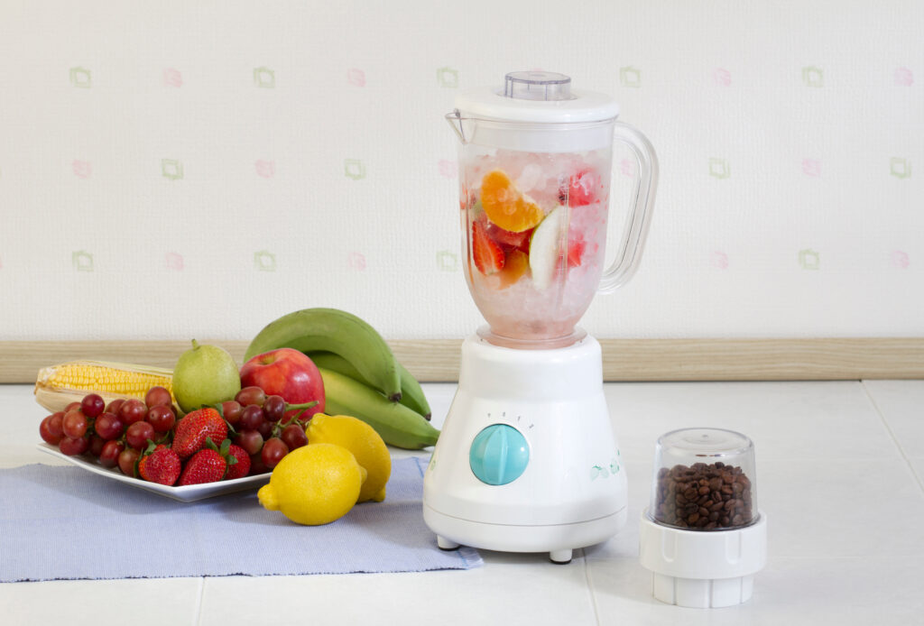 a portable blender next to fruit and a cloth on a table