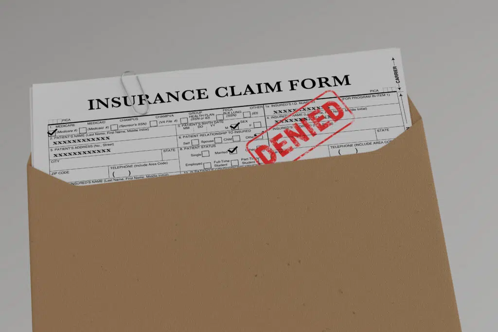 an insurance claim form filled out with a denial stamp on it after a car accident