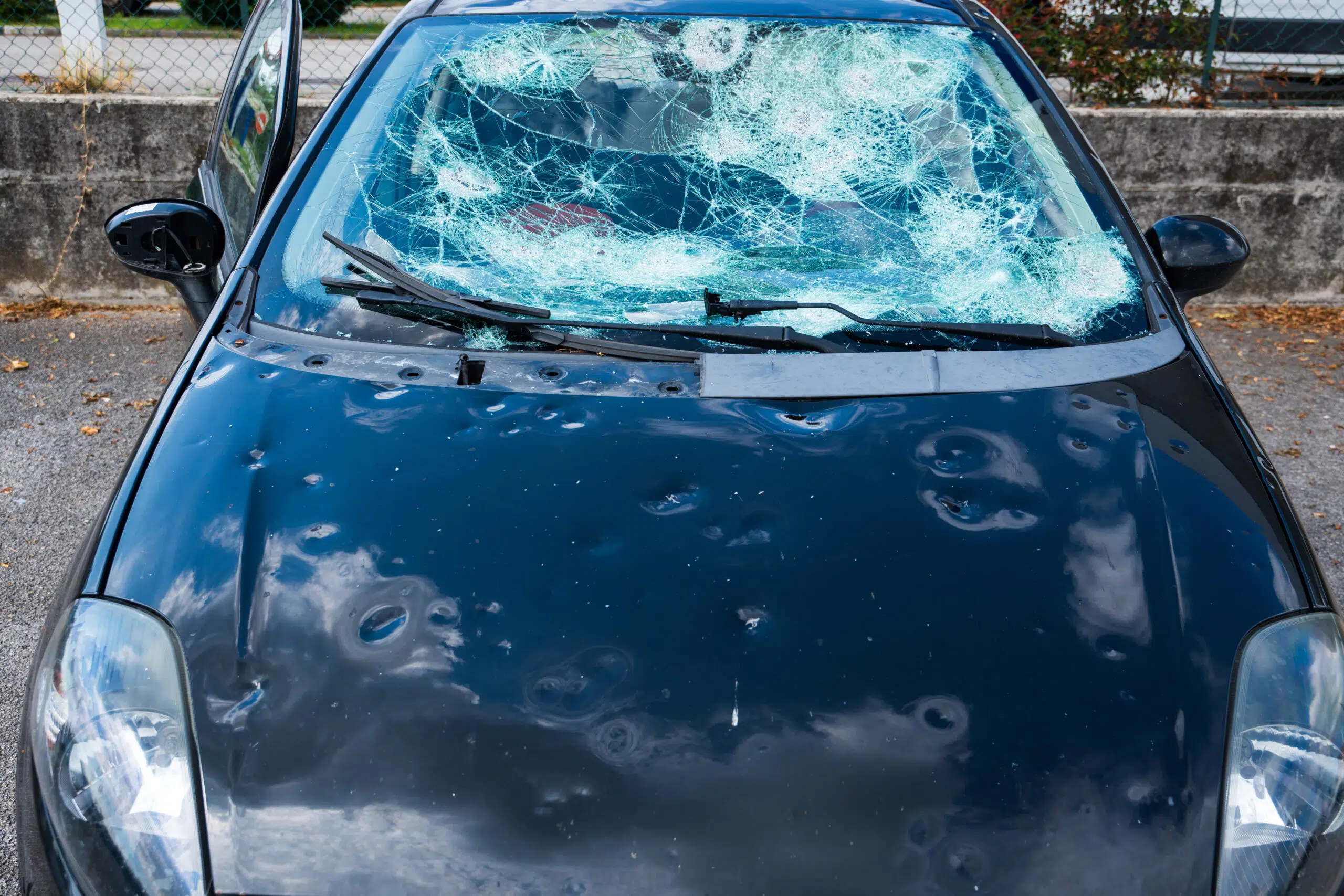 hail damage to car. damaged hood and windshield