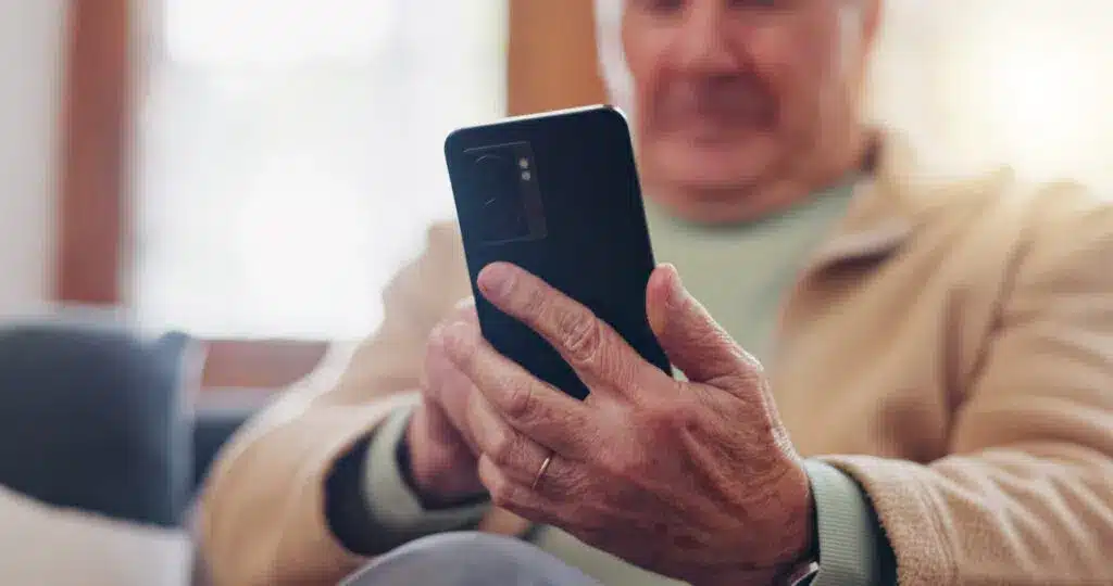 Elderly man posting on social media with a smart phone