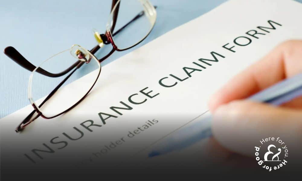 a persons hand filling out an insurance claim form on a table