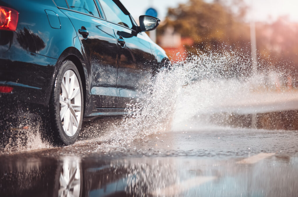 a car driving through a puddle on a rainy day and the tire splashing water