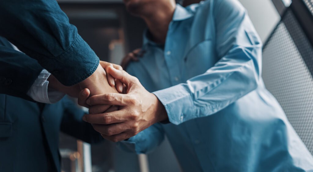 a client shaking hands with a car accident attorney wearing a business suit