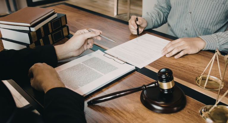 A person signing papers with their lawyer